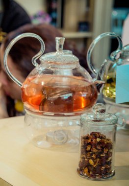 Cam çaydanlıkta demlenmiş bitki çayı ve şişede çay bitkisi.