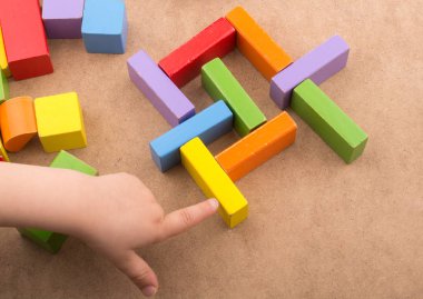 Yürümeye başlayan çocuk teslim et kahverengi arka plan üzerinde renkli yapı taşları