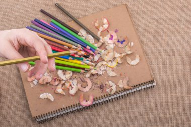 Kalem talaşı olan bir defterin üzerinde Renkli Kalem 'i tutarken