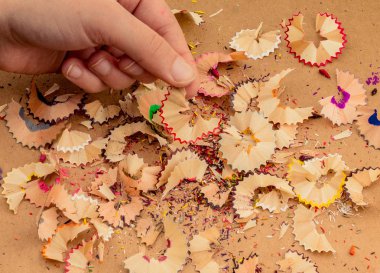 Elindeki renkli kalem talaşları bir deftere.