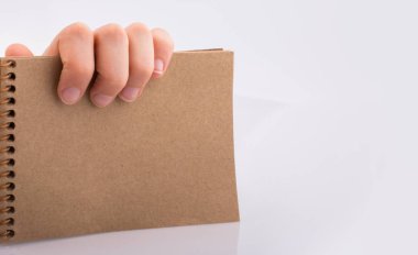 Beyaz arkaplanda kahverengi renkli bir not defteri var.