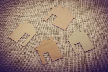 Tuvalin arka planında kağıttan yapılmış küçük bir ev şekli.