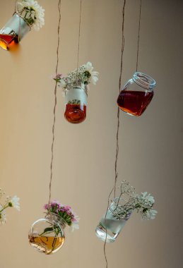 İplere asılı çiçekli bitkisel çay şişeleri
