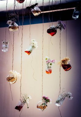 İplere asılı çiçekli bitkisel çay şişeleri