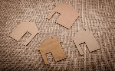 Tuvalin arka planında kağıttan yapılmış küçük bir ev şekli.