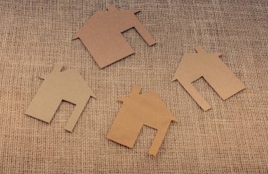 Tuvalin arka planında kağıttan yapılmış küçük bir ev şekli.