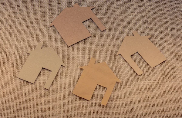 Tuvalin arka planında kağıttan yapılmış küçük bir ev şekli.