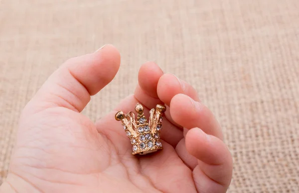 Hand holding a little model crown in hand