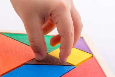 Tangram bulmacasının kayıp parçasını tutan el.