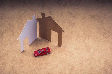 Kağıt ev ve arka planda model bir araba.