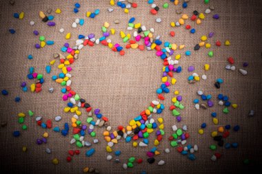 Renkli küçük çakıl tuval zemin üzerinde bir kalp şeklini