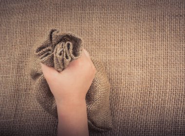 Çarşaftan yapılmış boş bir çuvalı tutan el.