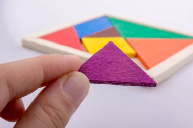 Tangram bulmacasının kayıp parçasını tutan el.
