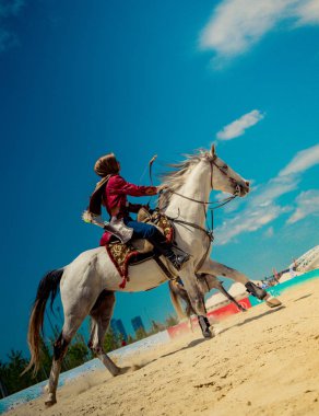 Osmanlı atlısı etnik kıyafetleriyle atına biniyor.