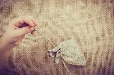 Çarşaftan yapılmış boş bir çuvalı tutan el.