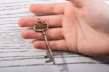 Ahşap doku üzerinde bir retro tasarımlı dekoratif anahtar tutan el