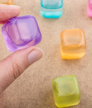 Sahte renkli Ice cube kahverengi arka planda tutan el
