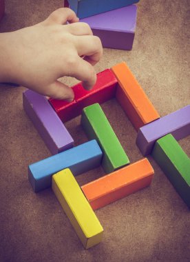 Yürümeye başlayan çocuk teslim et kahverengi arka plan üzerinde renkli yapı taşları