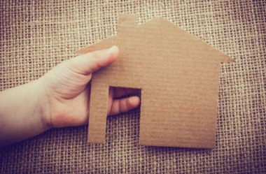 Tuvalin arka planında bir bez evi tutan el.