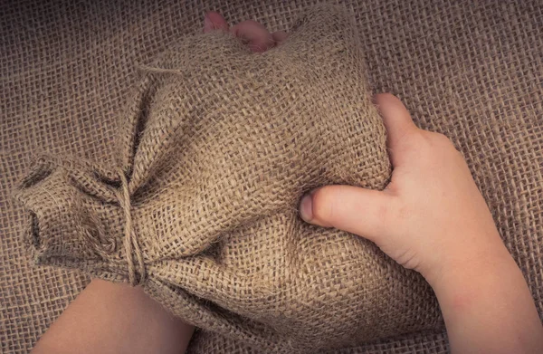 Hand holding an empty little sack made of linen