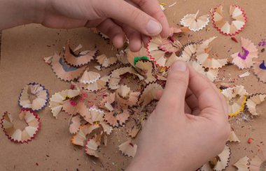 Elindeki renkli kalem talaşları bir deftere.