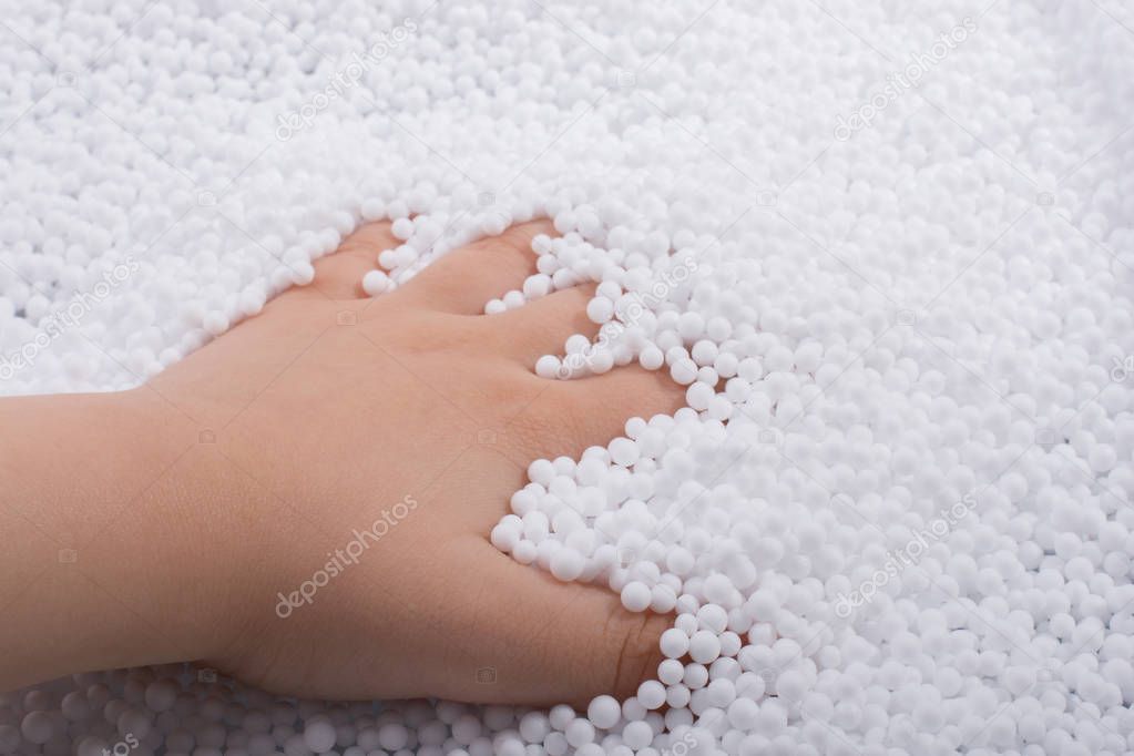 Toddler hand in White polystyrene foam balls as background