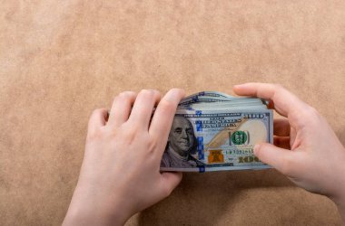 El ele tutuşan Amerikan doları banknotları ahşap arka planda izole edilmiş.