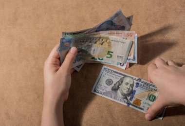 El ele tutuşan Amerikan doları banknotları ahşap arka planda izole edilmiş.