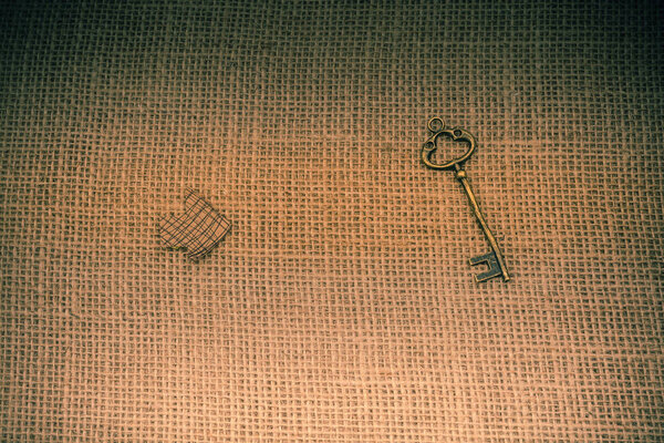 Retro key and an arrow cut out of brown paper on canvas