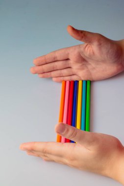 Beyaz arkaplana yerleştirilmiş el ele tutuşan kalemler