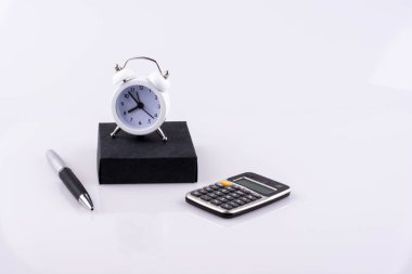 çalar saat, hesap makinesi, kalem ve defter beyaz bir arka plan üzerine yerleştirilen