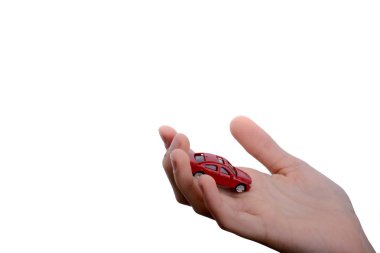 Çocuğun eli beyaz arka planda kırmızı bir arabayı tutuyor.
