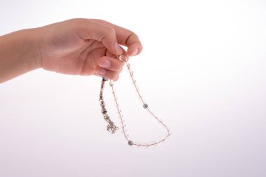 Beyaz bir arka plan üzerinde bir tespih tutan el