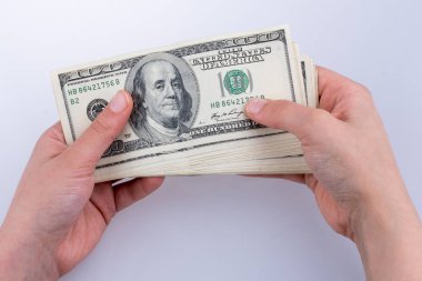 İnsan eli, Amerikan doları banknotunu beyaza izole edilmiş olarak tutuyor.