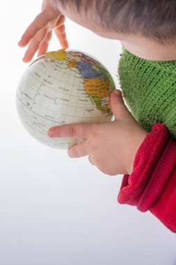 Beyaz arka planda bir küreyi tutan çocuk