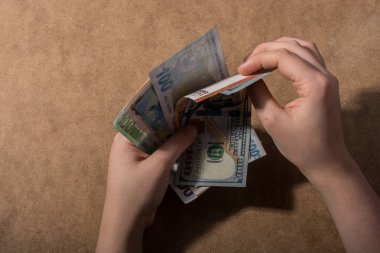 El ele tutuşan Amerikan doları banknotları ahşap arka planda izole edilmiş.