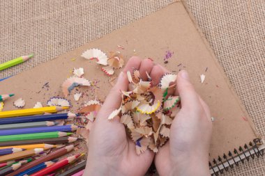 Elindeki renkli kalem talaşları bir deftere.