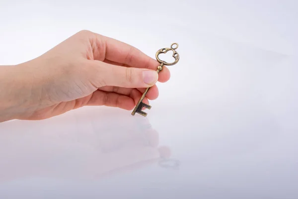 Χέρι Κρατώντας Ένα Κλειδί Λευκό Φόντο — Φωτογραφία Αρχείου
