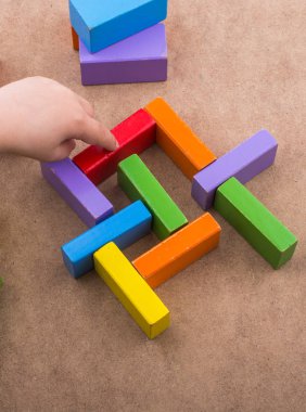 Yürümeye başlayan çocuk teslim et kahverengi arka plan üzerinde renkli yapı taşları