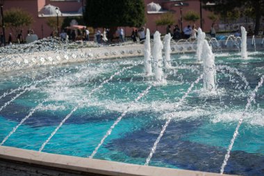 Çeşmeler parktaki bir havuzda köpüklü su fışkırtıyor.