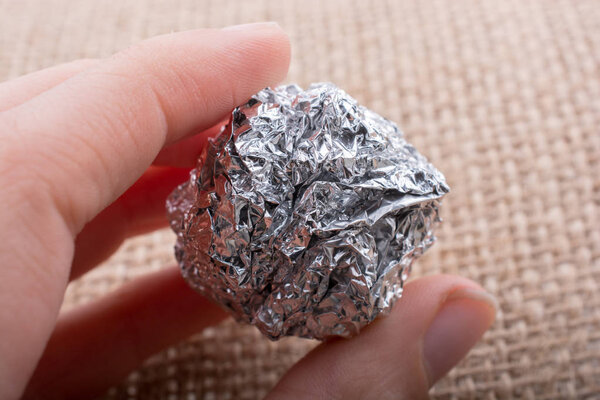 Aluminium foil in the shape of a sphere on a textured background