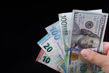 El ele tutuşan Amerikan doları banknotları siyah arka planda izole edilmiş.