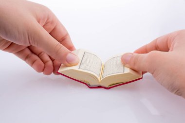 Beyaz arka planda Kuran 'ı el ele tutuşarak.