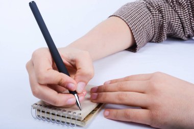 Çocuk el üstünde bir spiral defter beyaz zemin üzerine kalemle yazma