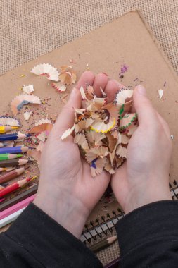 Elindeki renkli kalem talaşları bir deftere.