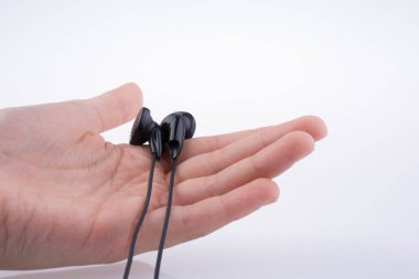 Beyaz arka planda siyah bir kulaklık tutuyor.