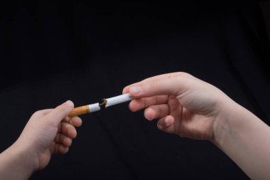 El siyah arka planda sigara kırıyor.