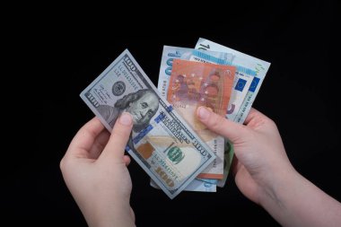 El ele tutuşan Amerikan doları banknotları siyah arka planda izole edilmiş.