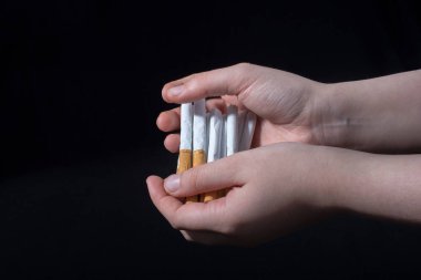 El, siyah arka planda bir paket sigara dağıtıyor.