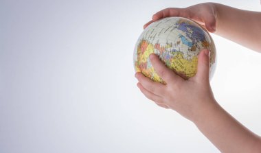 Beyaz arka planda bir küreyi tutan çocuk
